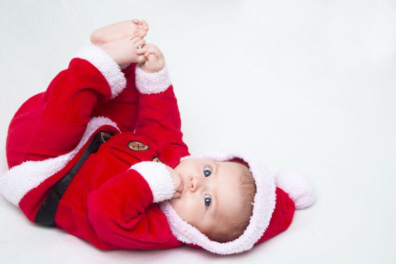 快乐的宝宝躺在地上穿着一件红白相间的圣诞套装