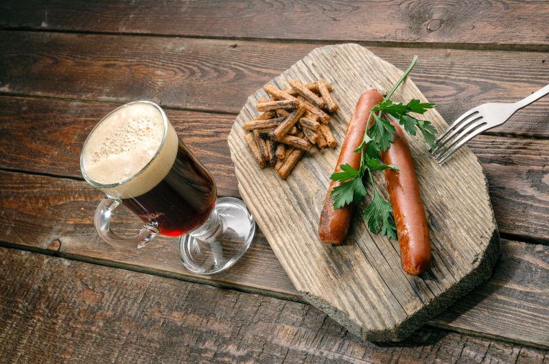 木纹理桌上的砧板上的烤香肠与啤酒