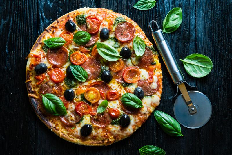 黑色木制背景下的意大利腊肠披萨
